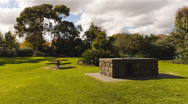 Barbeque pit and park bench in Ardrie Park