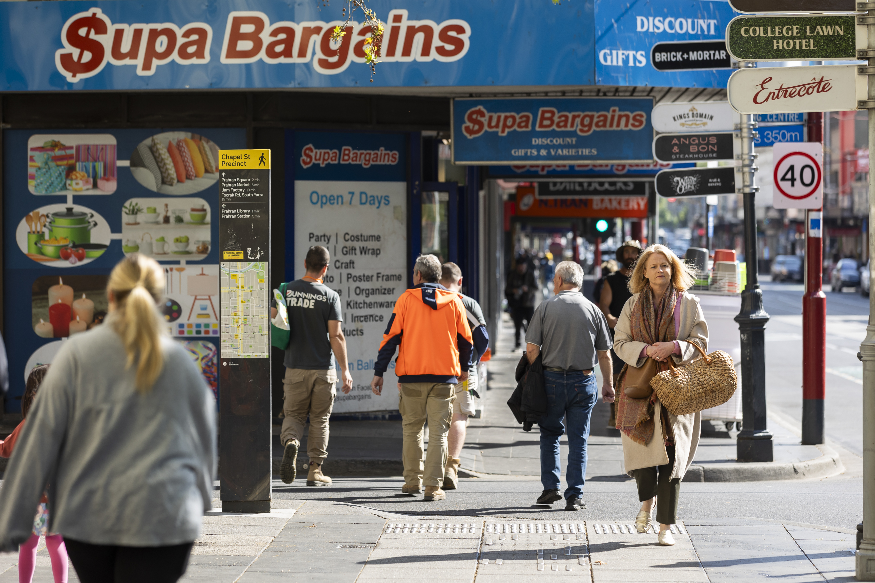 Suburban shops with people crossing road in the foreground.