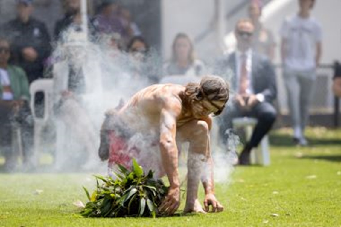 Indigenous_man_bending_down_over_smoking_gumleavesJanuary 2023_CoS_event.jpg