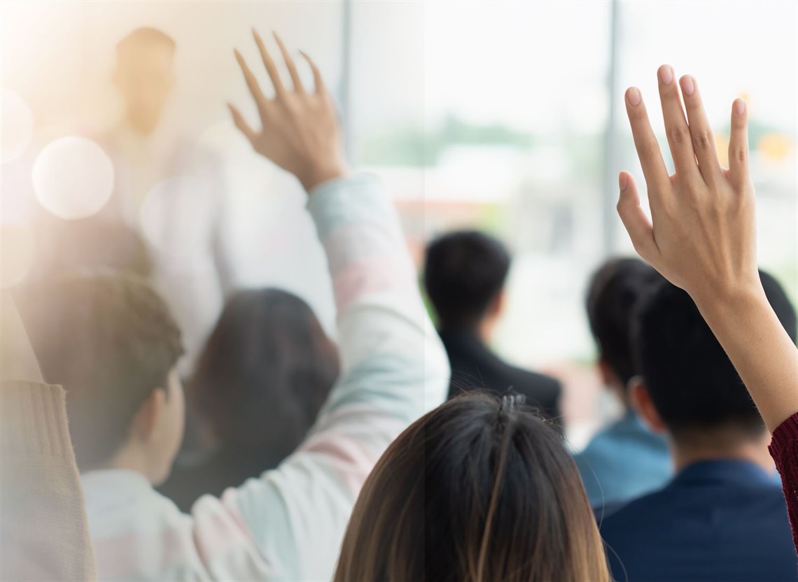 People with hands up in info session