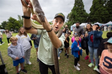 Man holding a snake in front of crowd