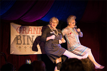 Two people performing onstage dressed as grannies