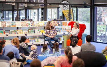 Two women reading story to families